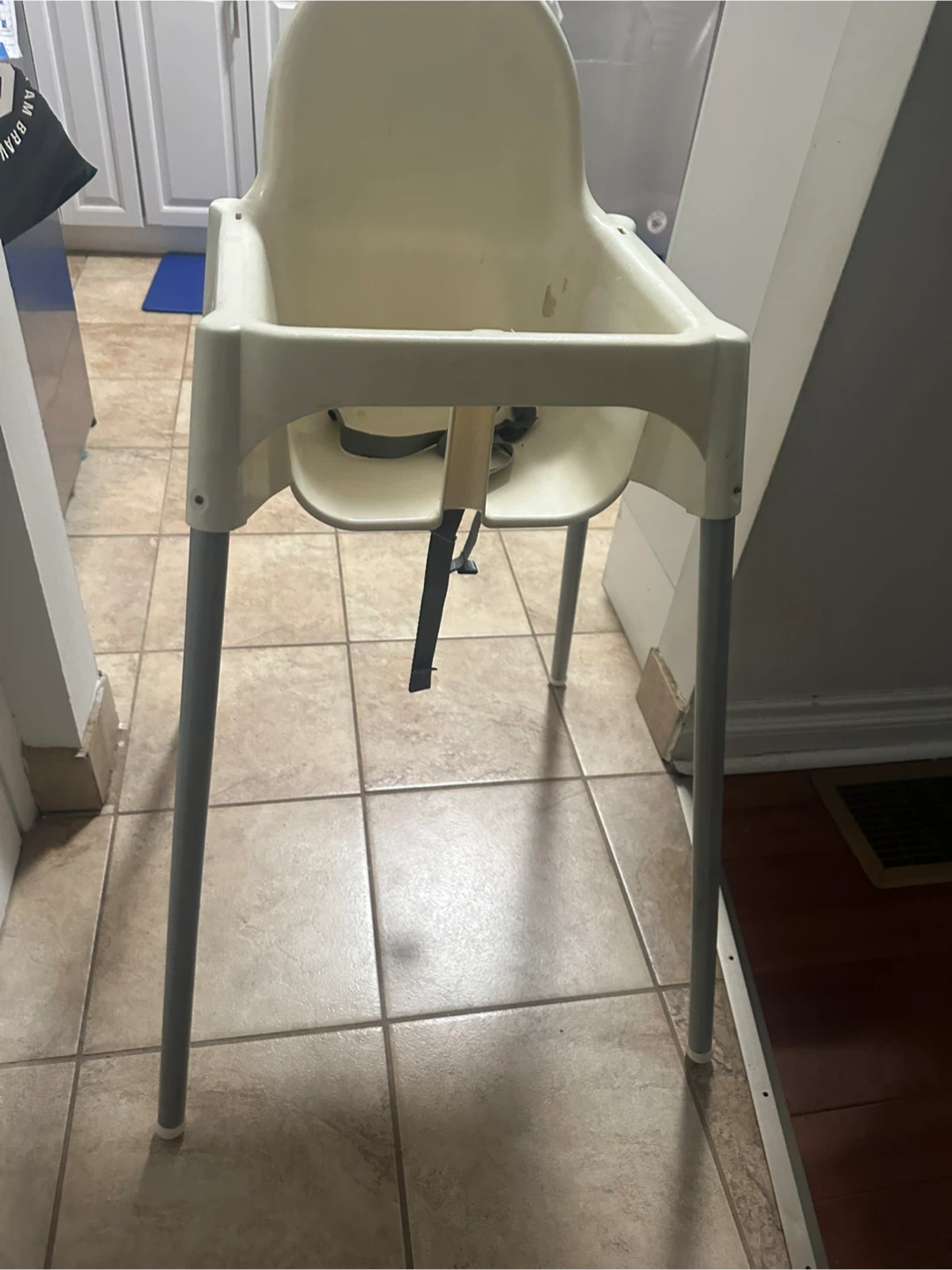 Cream coloured plastic high chair with grey legs