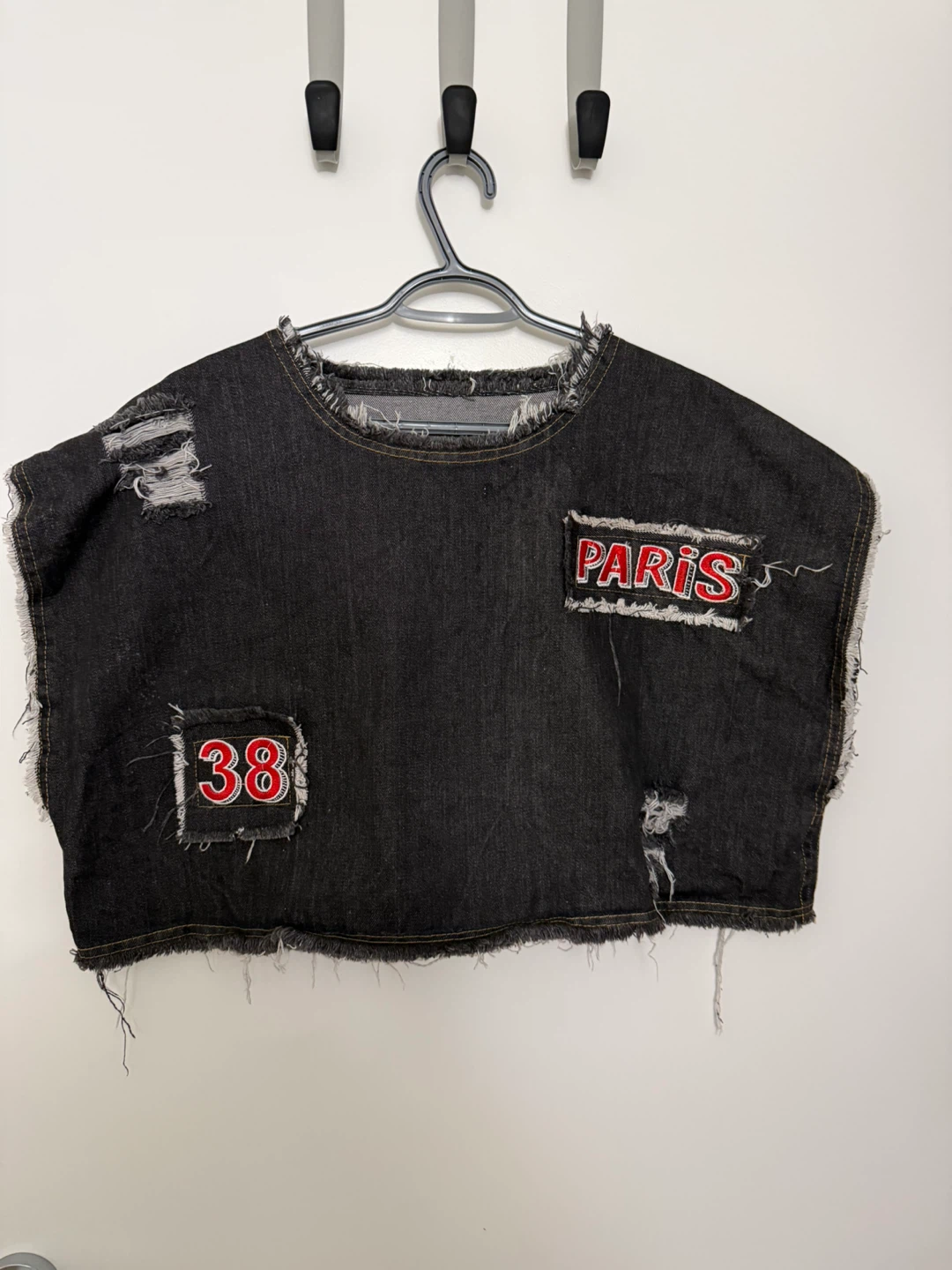Distressed denim crop top with raw edges and graphic details.