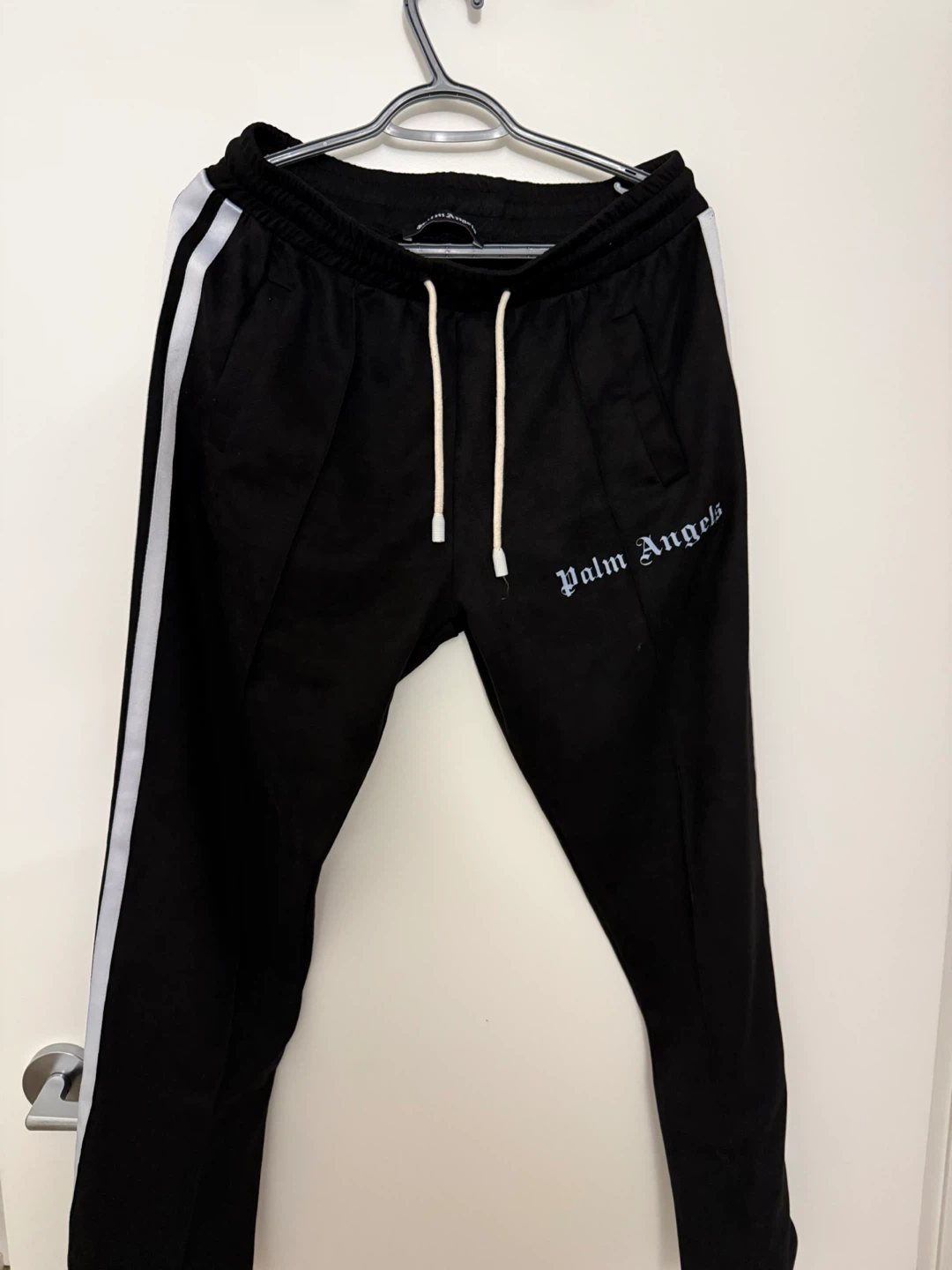 Black track pants with Palm Angels style and side stripe design.
