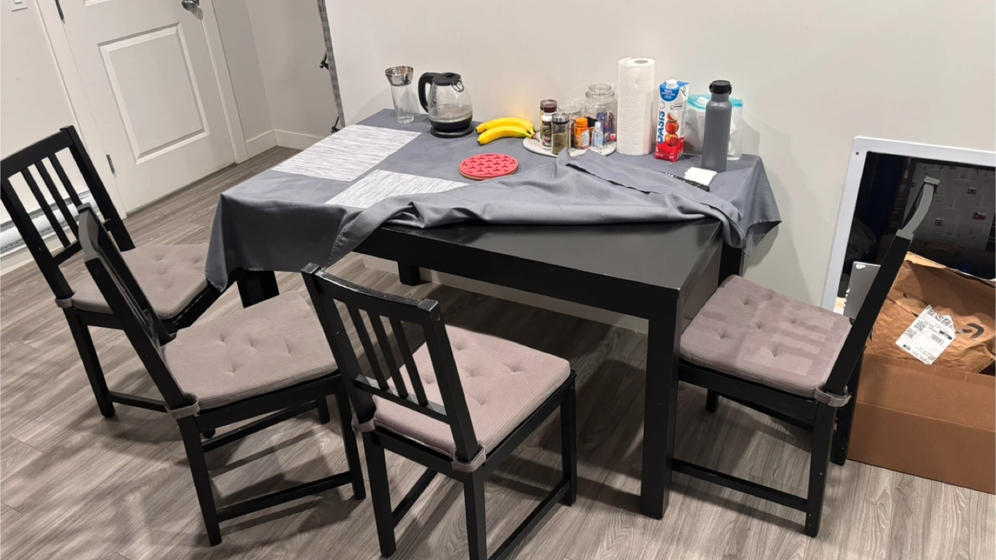 Four black dining chairs with grey cushions