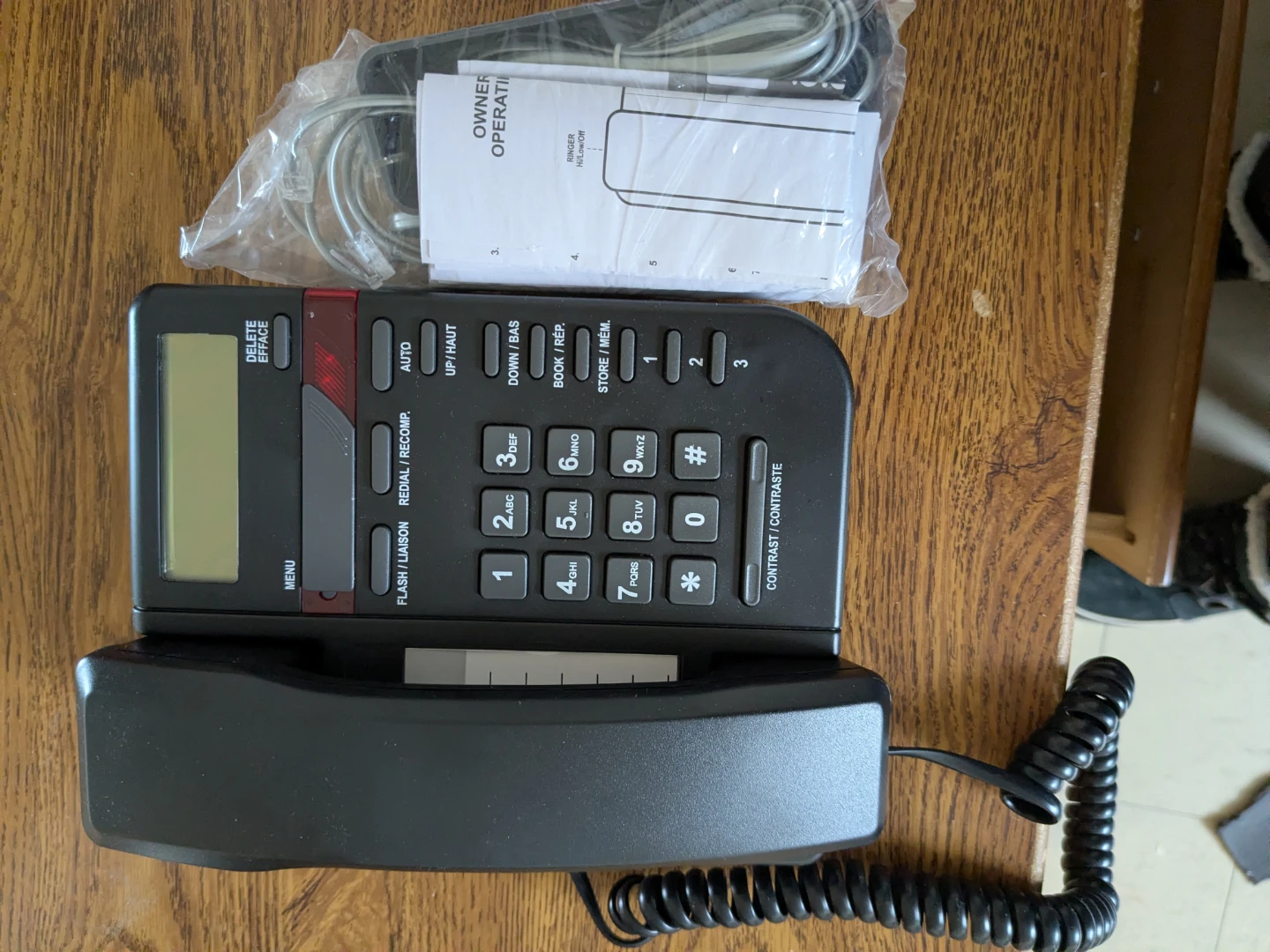 Black corded office phone with manual