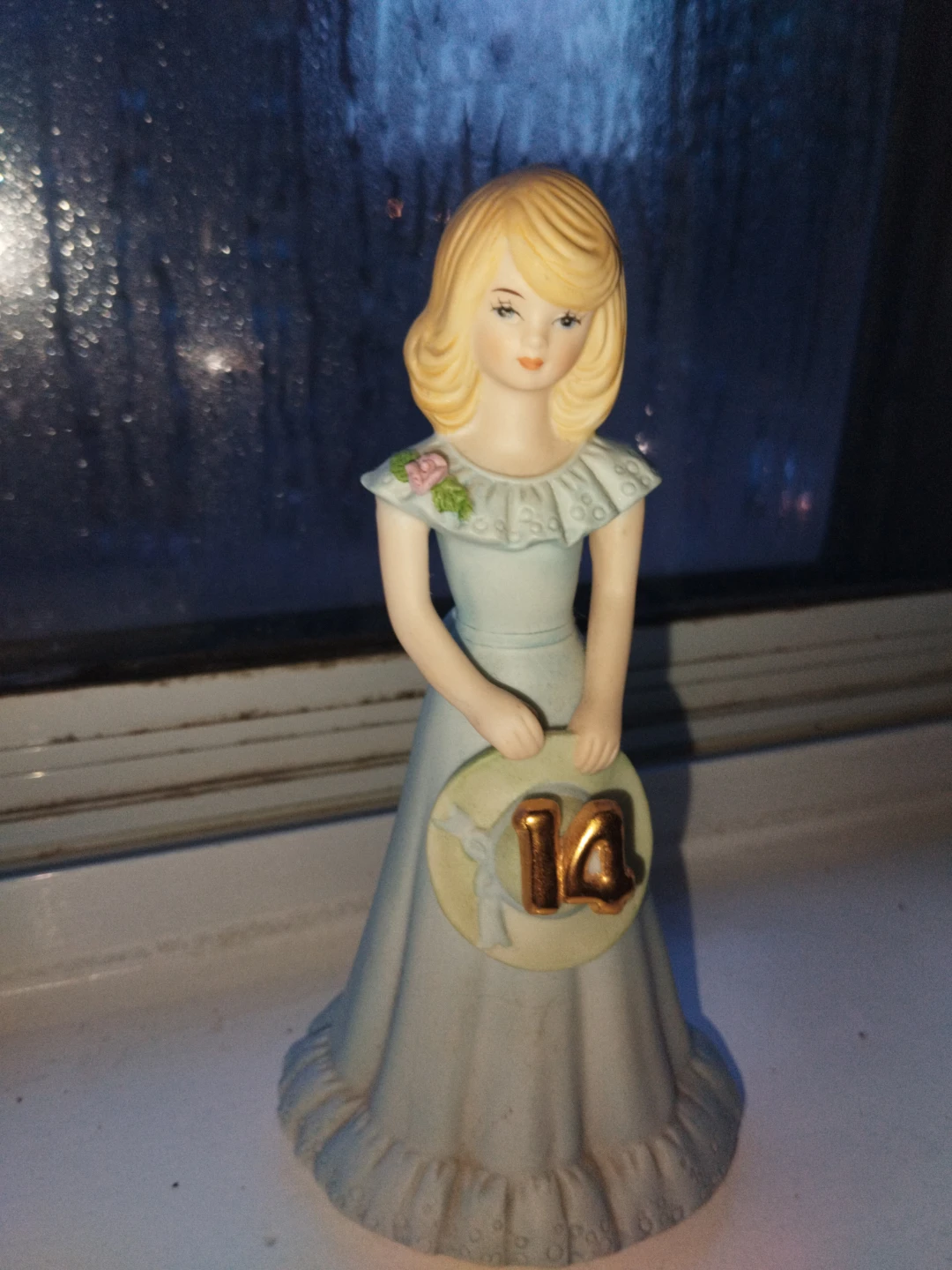 Figurine of a girl holding a '14' sign