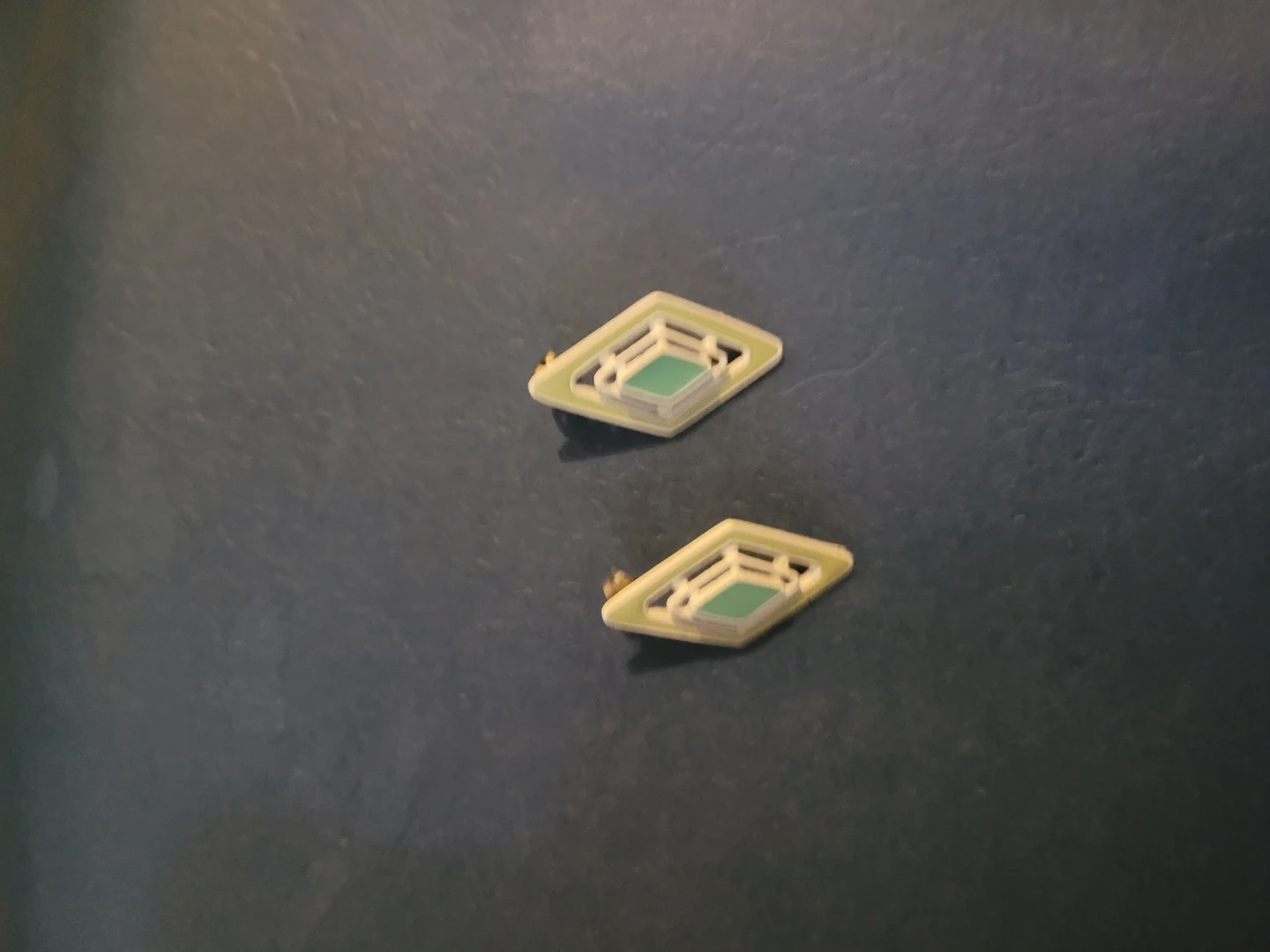 Two diamond-shaped decorative pins