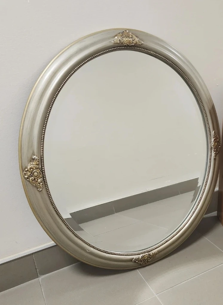 Oval decorative mirror with ornate silver frame