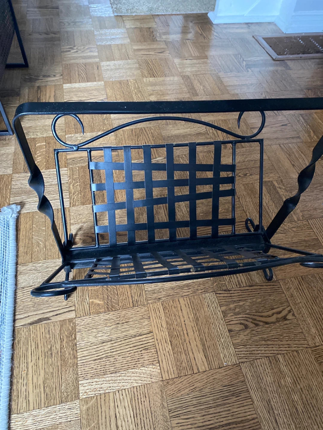 Black metal magazine rack with decorative scrollwork