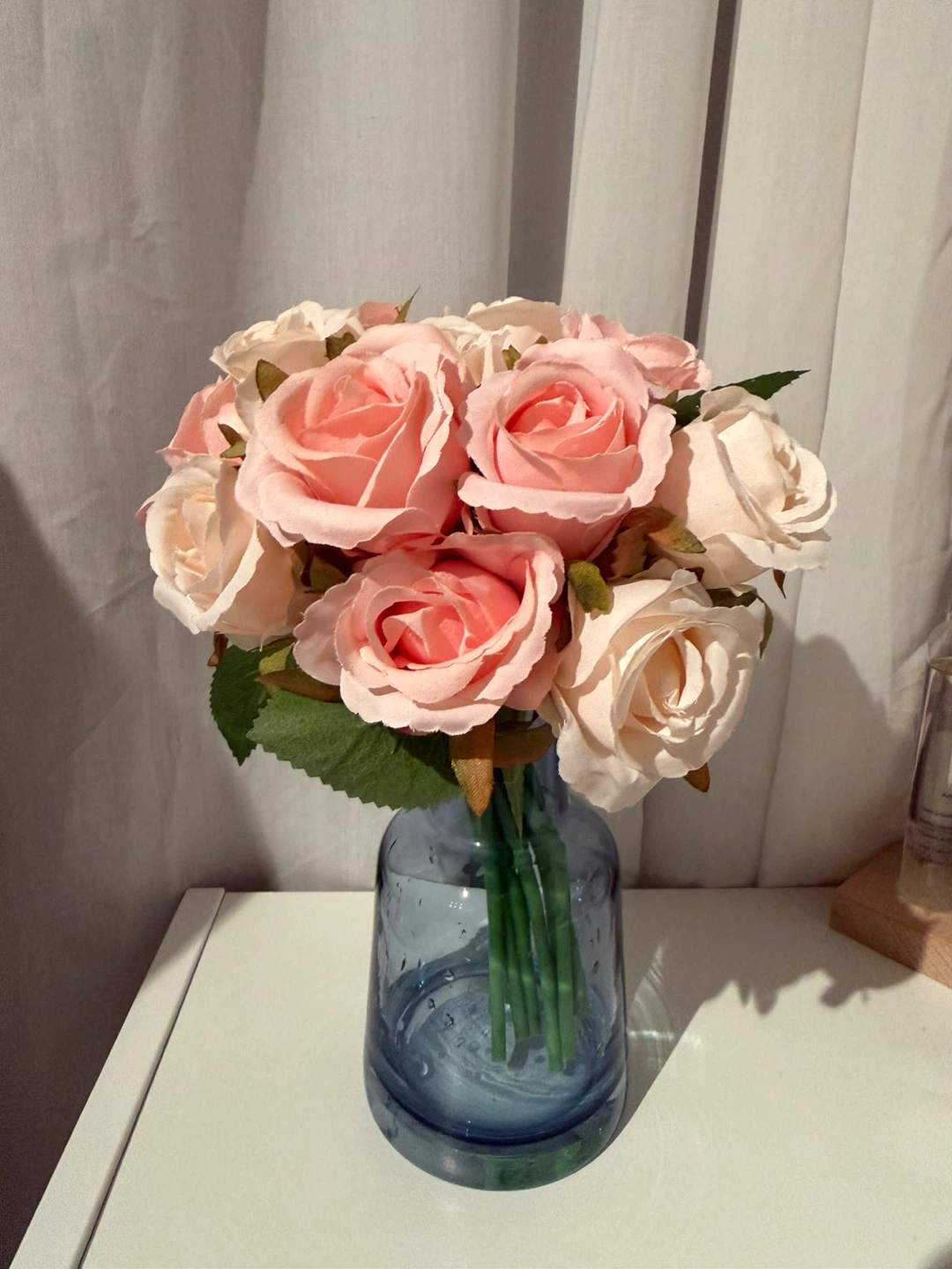 Blue glass vase with a bouquet of artificial roses