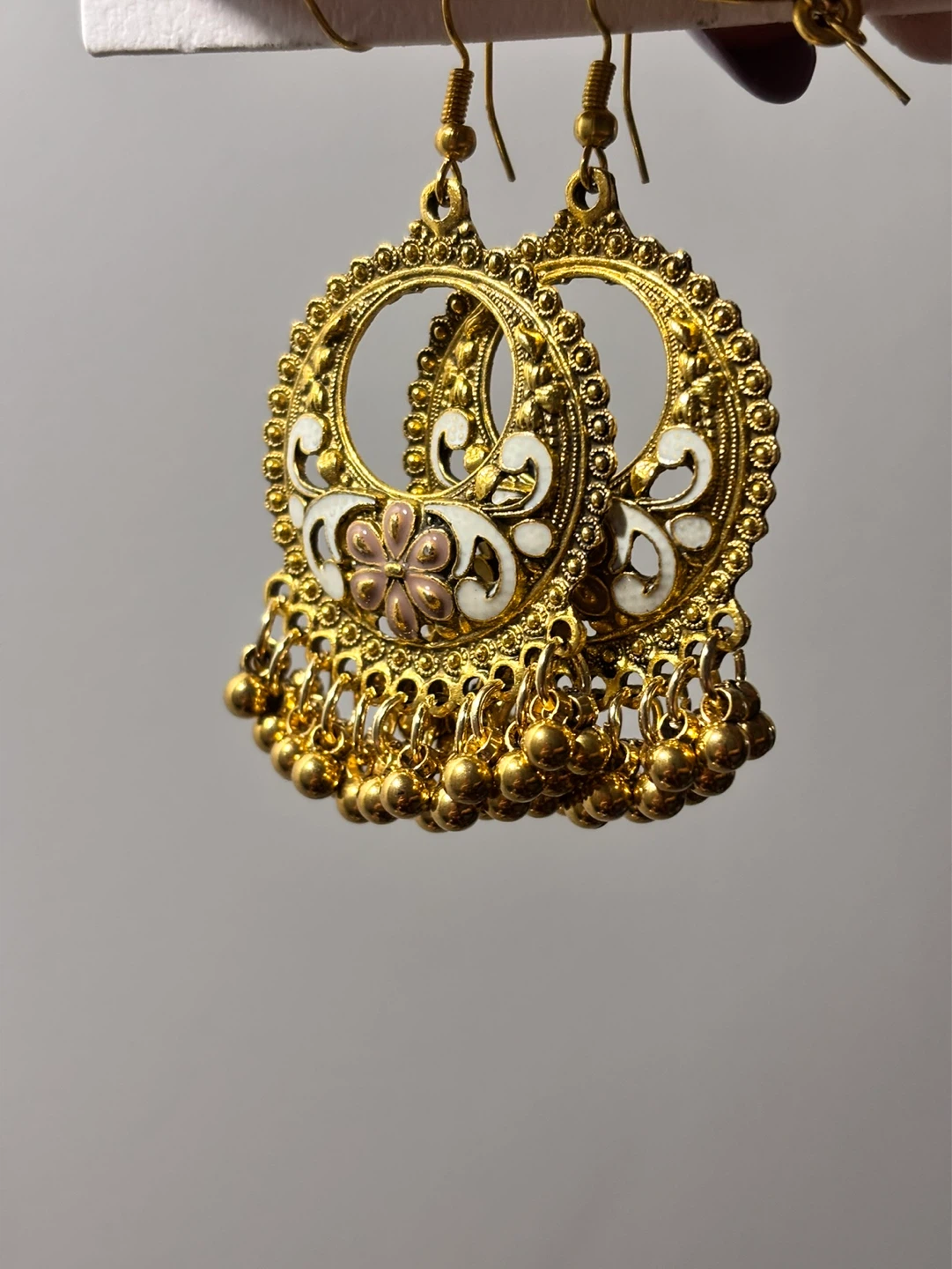 Gold coloured jhumka earrings with decorative details