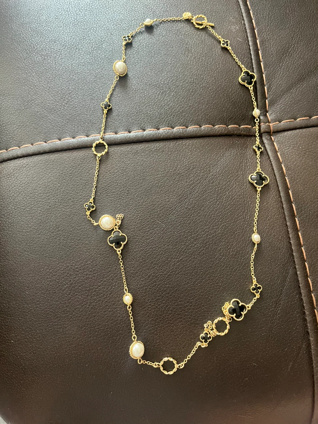 Gold-tone necklace with black clover charms and pearls