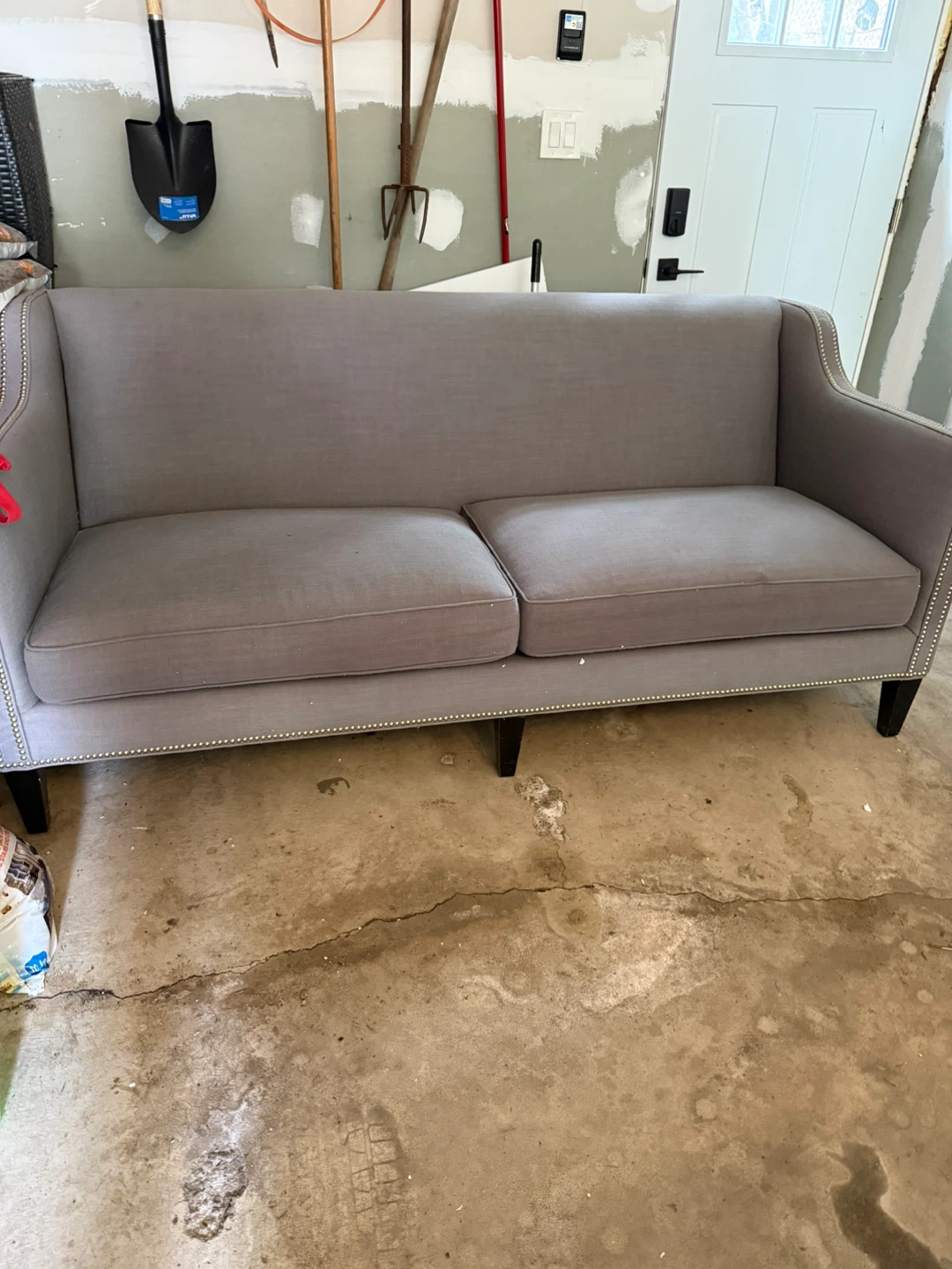 Grey upholstered loveseat with silver nailhead trim