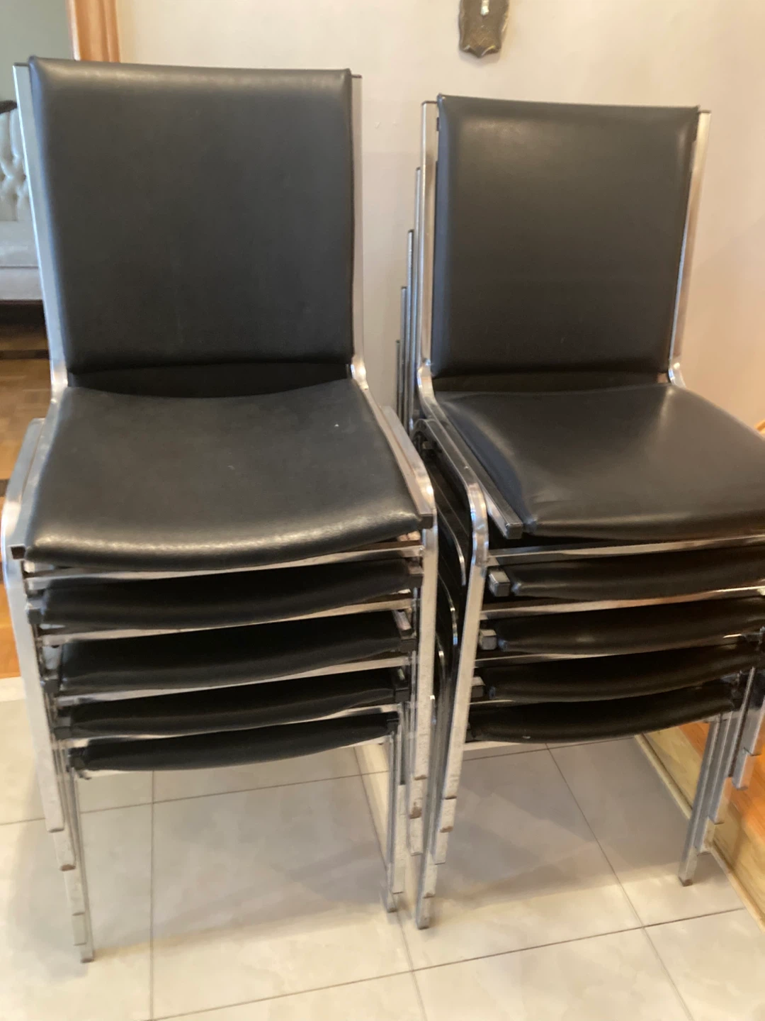 10 stackable chairs with black padded seats and backs.