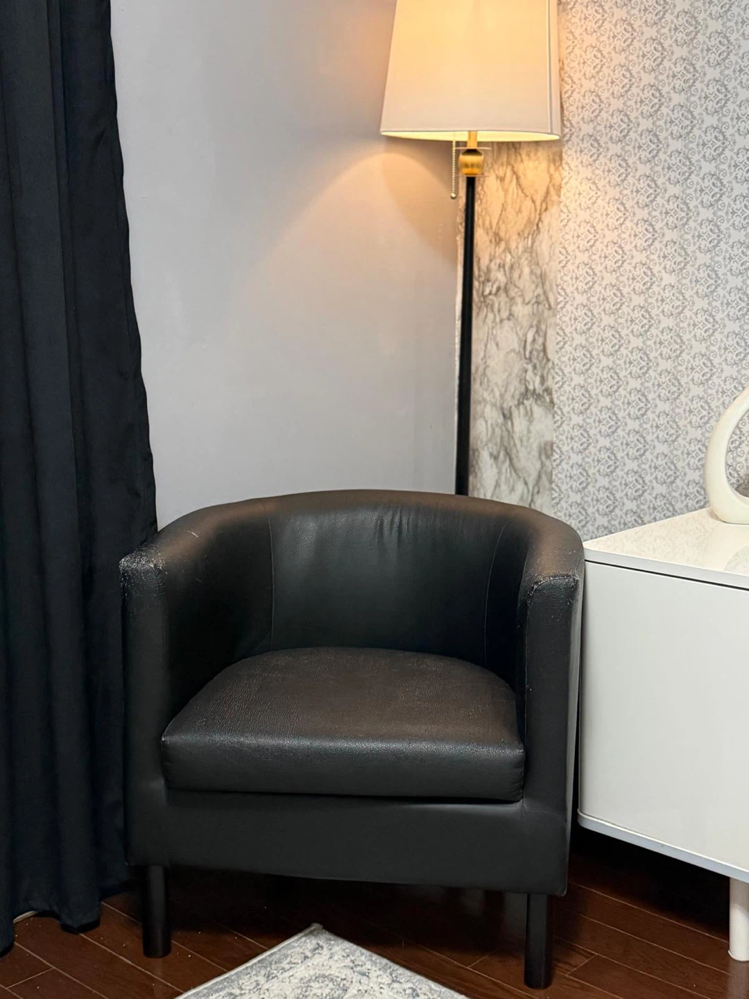 Black accent chair with "stay awhile" pillow