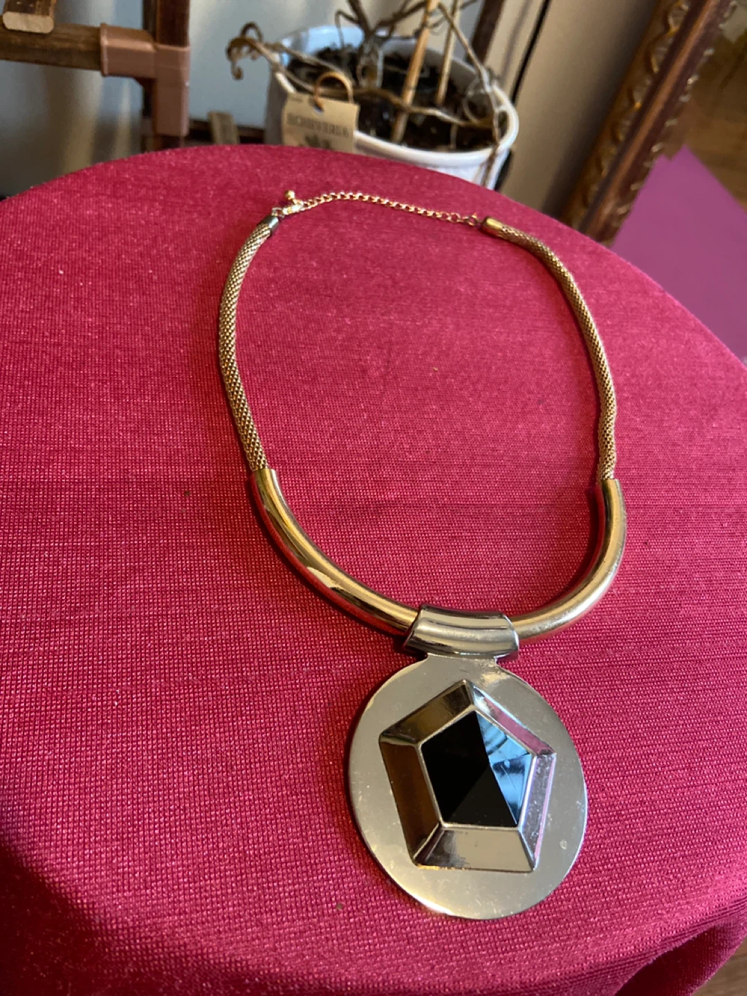 Gold-tone statement necklace with black and silver pendant