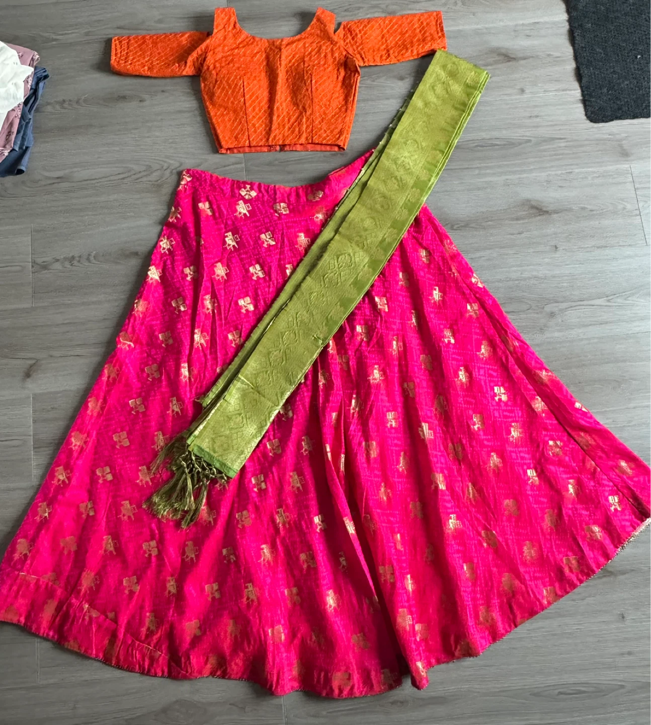 Orange blouse with pink lehenga skirt and green dupatta
