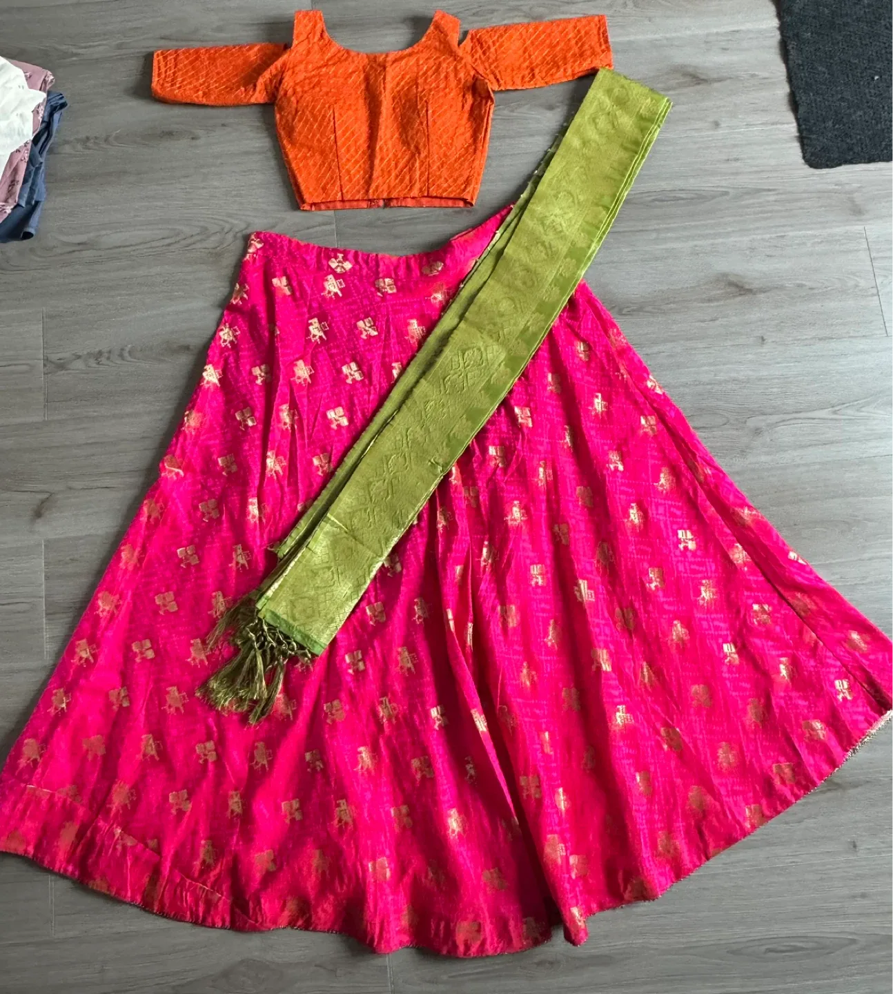 Orange blouse with pink lehenga skirt and green dupatta