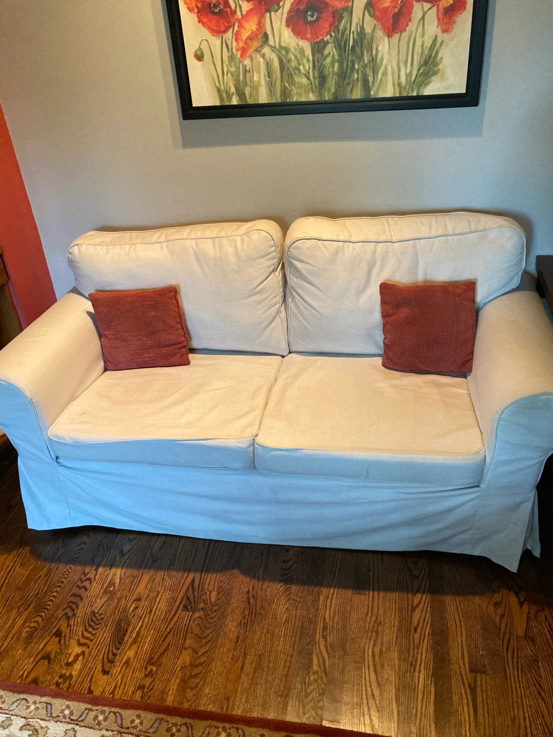 Ektorp Beige Two-Seater Sofa with Two Red Throw Pillows