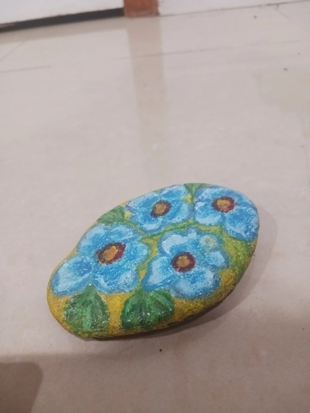 Hand-painted decorative rock with blue flowers