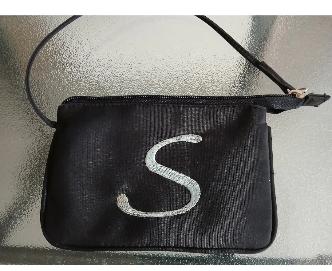 Black wristlet with embroidered 'S'.