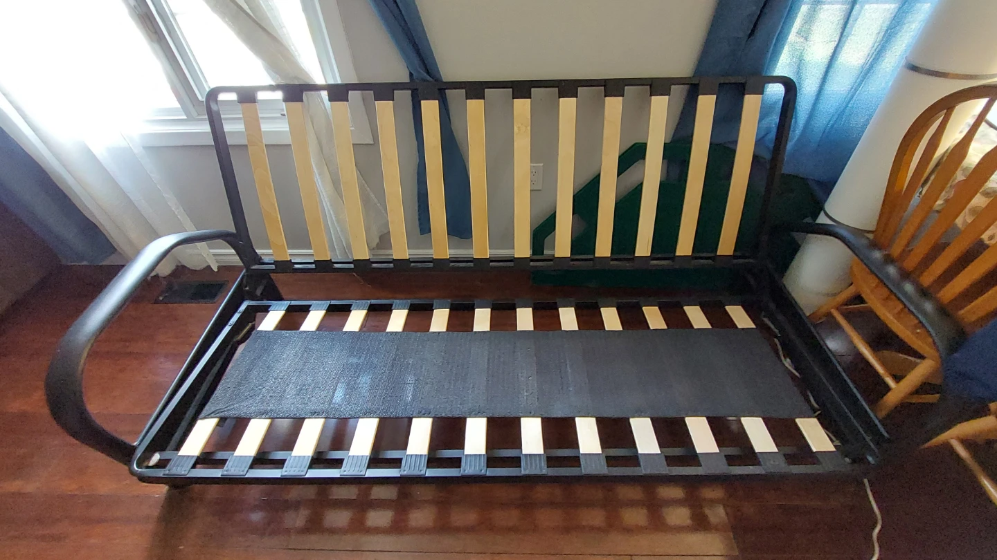 Solid black metal futon frame with wooden slats