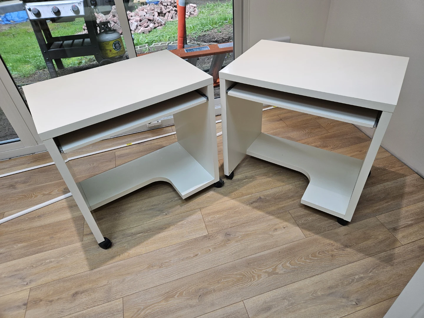 Two white IKEA computer desks with keyboard trays