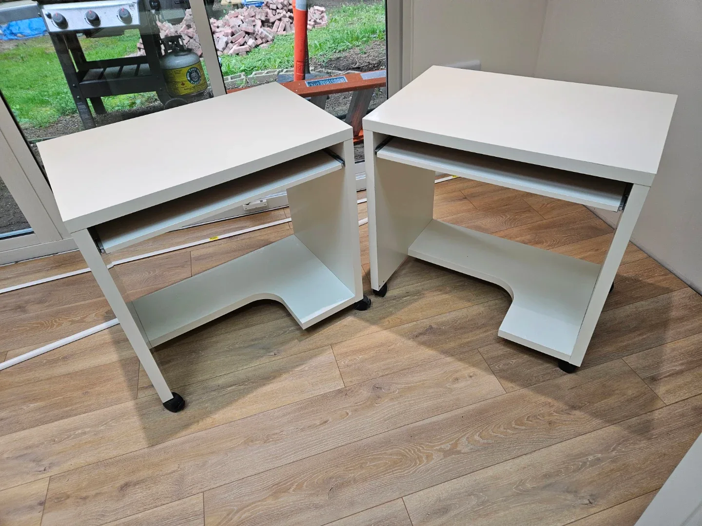 Two white IKEA computer desks with keyboard trays