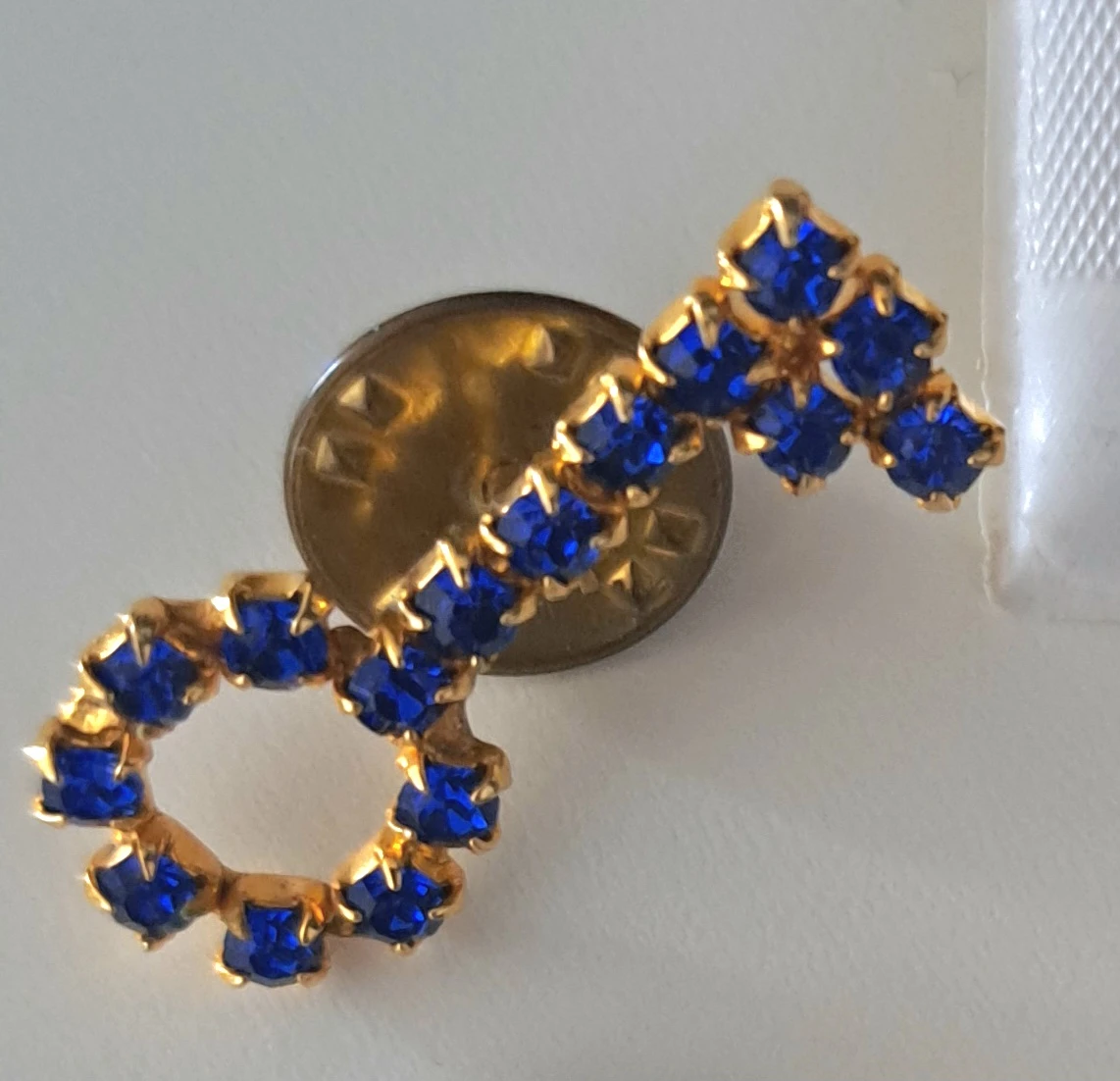 Gold tone lapel pin with blue rhinestones