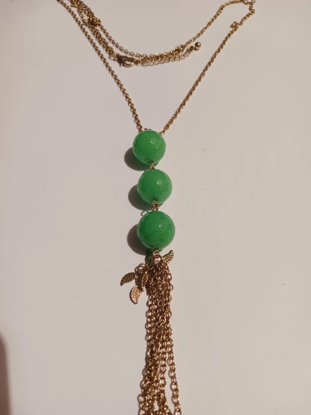 Gold tone necklace with green beads and tassel