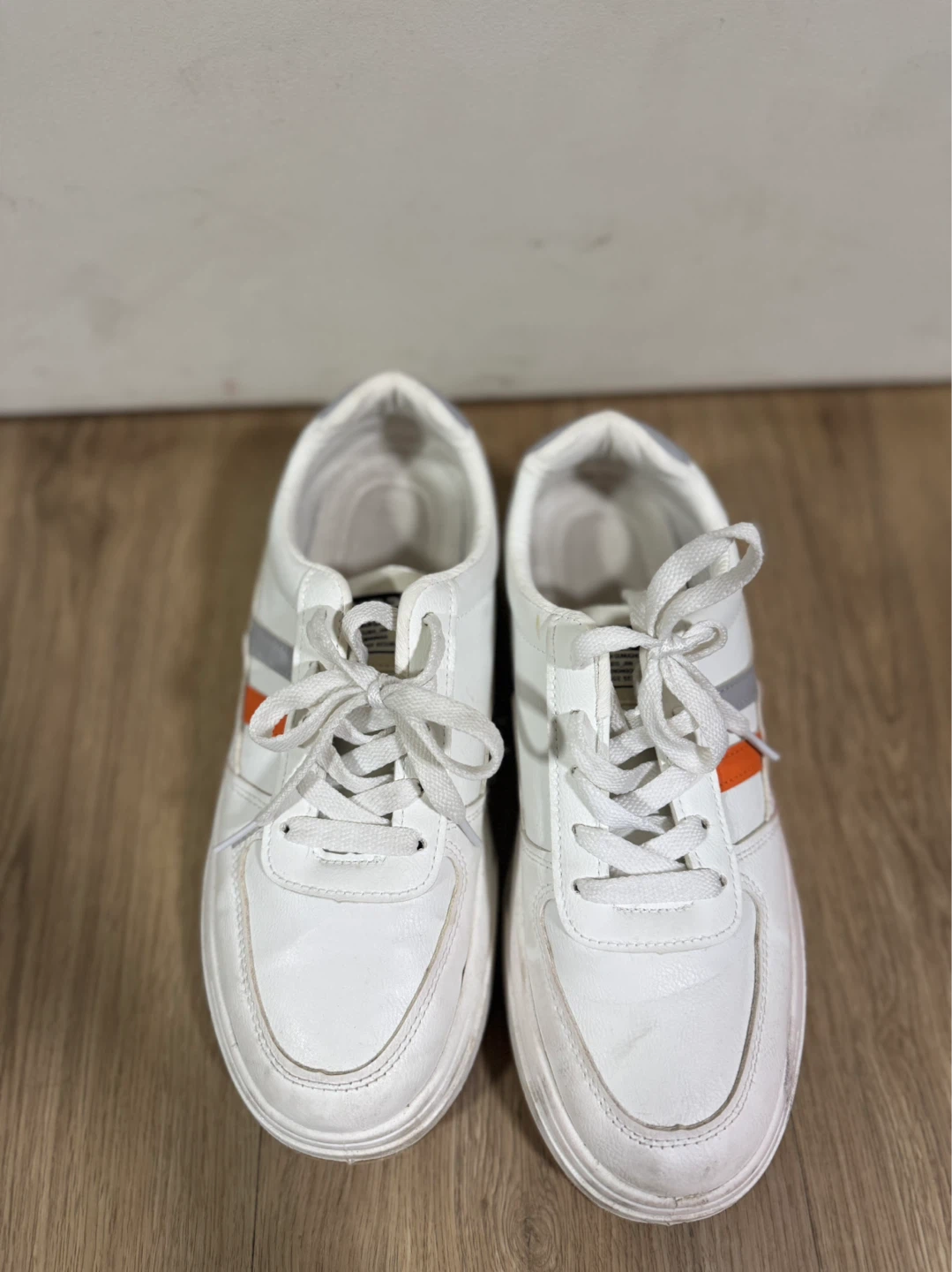 White fashion sneakers with orange and grey stripe accents
