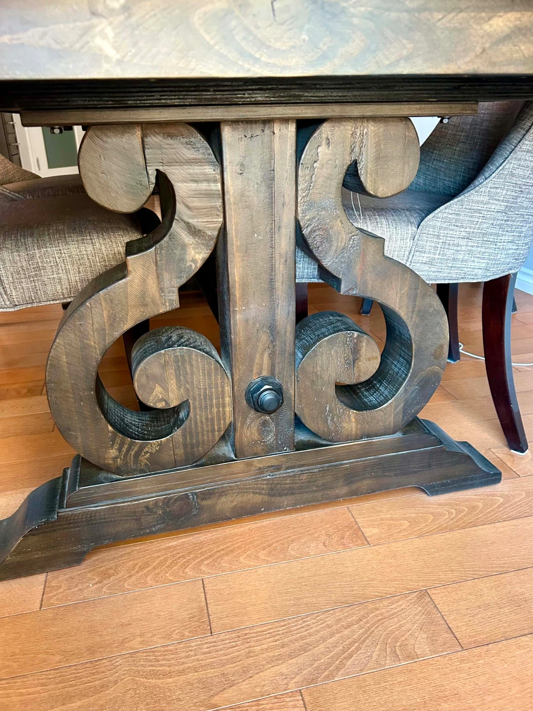 Solid carob wood dining table and six grey fabric chairs.