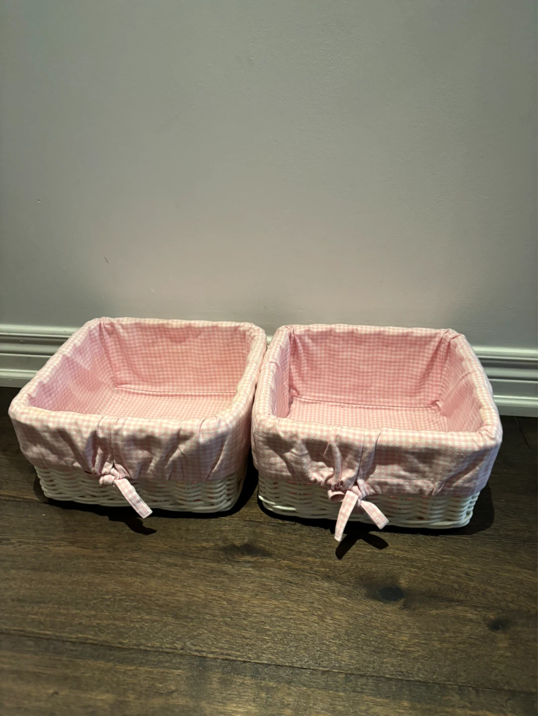 A set of 2 white wicker baskets with pink gingham liner