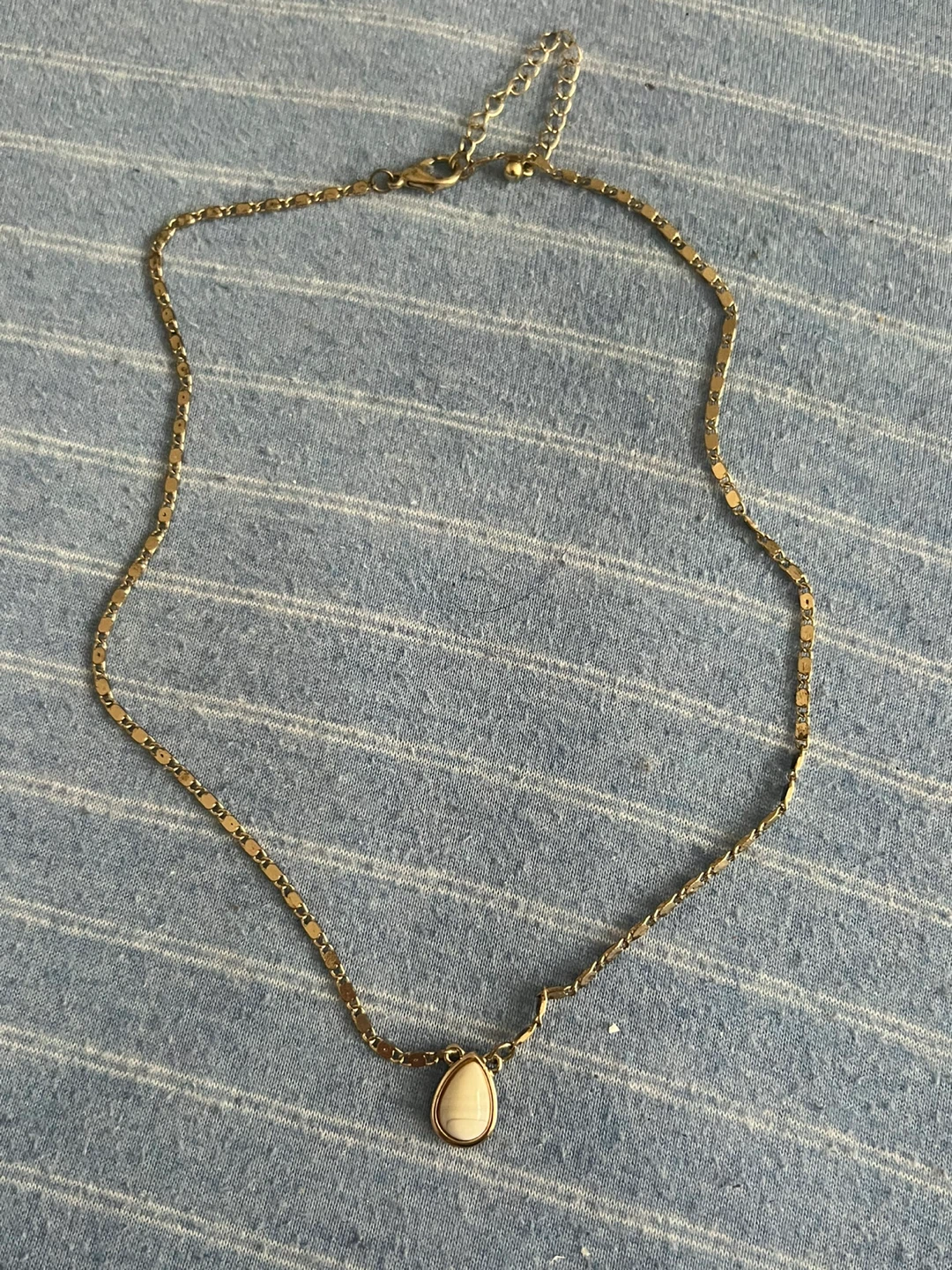 Gold tone necklace with white pendant