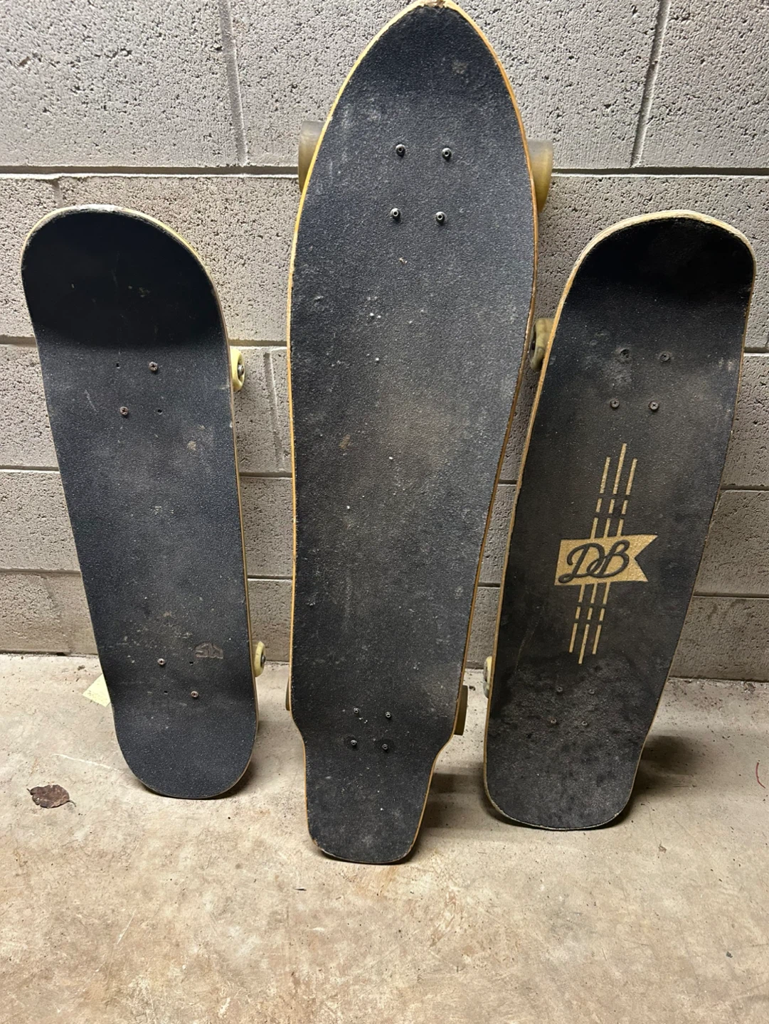 Three Skateboards - Two Black, One with DB Logo