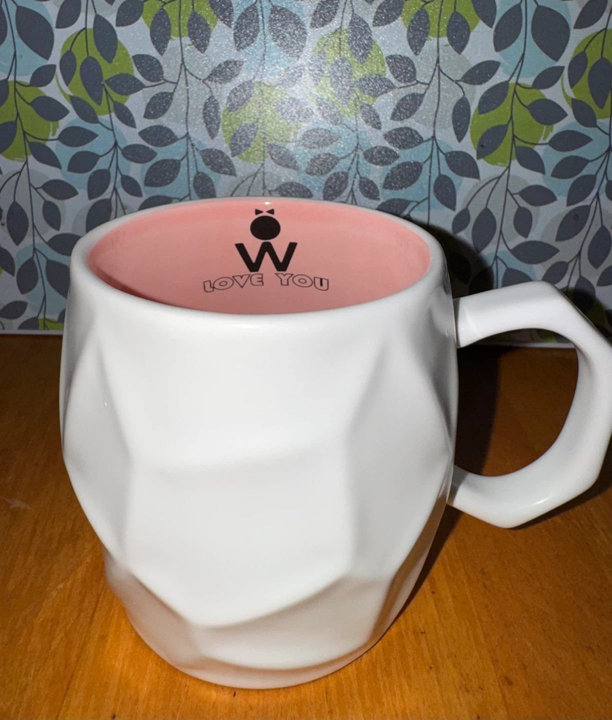 White ceramic mug, pink interior.  “Love you” bee
