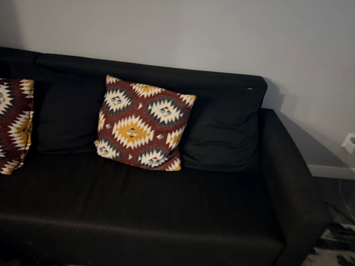 Black sectional couch with patterned throw pillows - photo 2