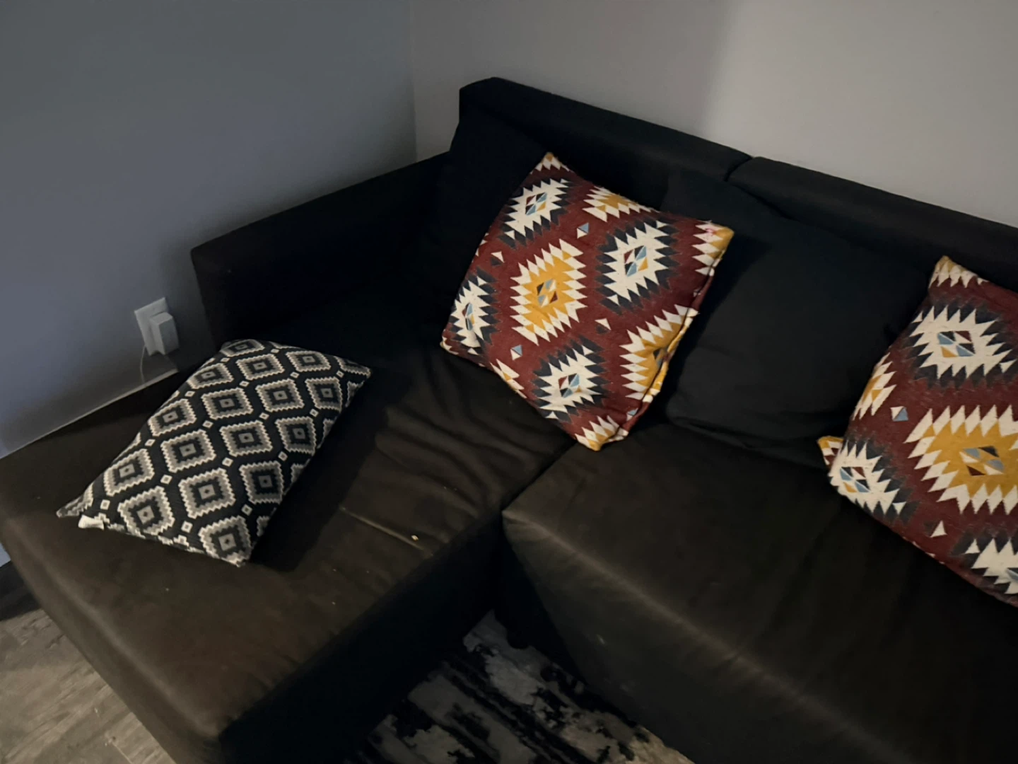 Black sectional couch with patterned throw pillows