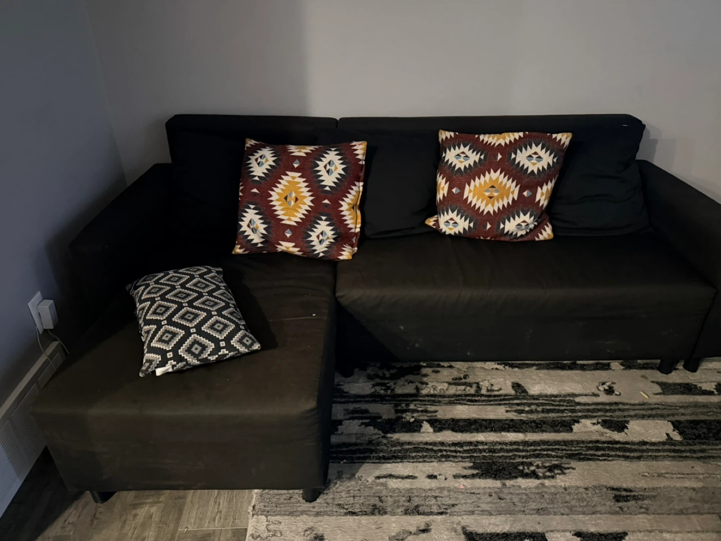 Black sectional couch with patterned throw pillows - photo 3