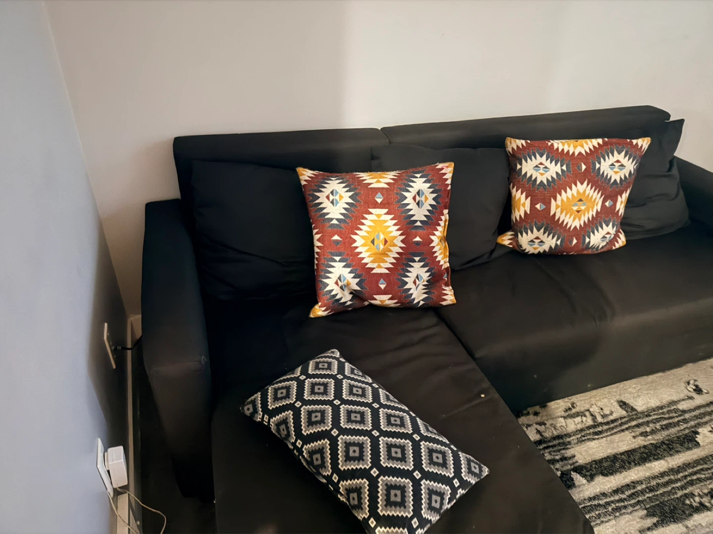 Black sectional couch with patterned throw pillows - photo 5