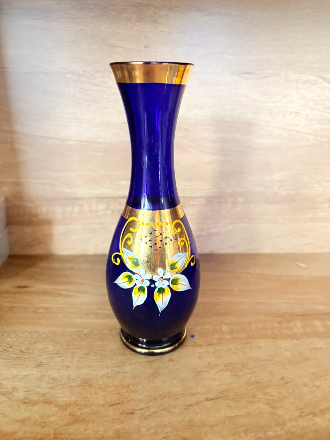 Blue glass vase with gold trim and floral detail