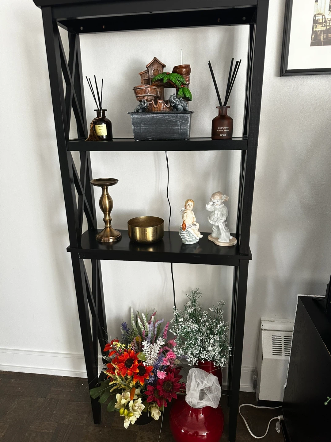 Black leaning bookshelf with decorative items