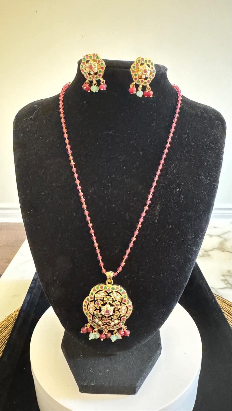 Gold coloured pendant and earrings set with pink beads