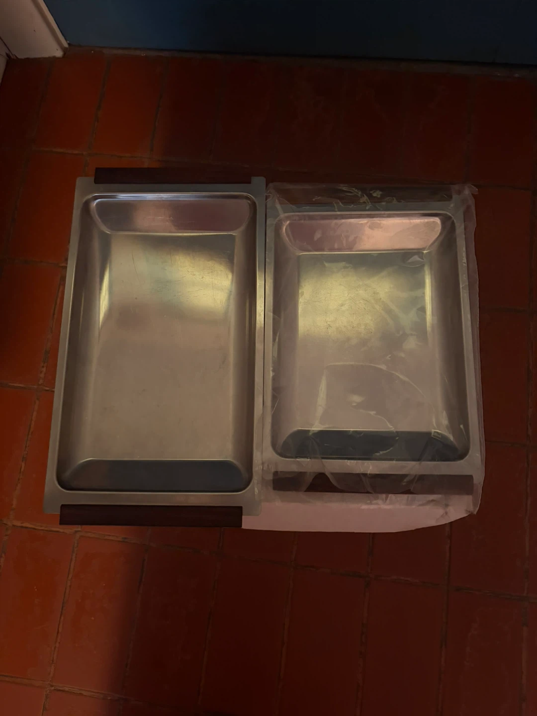 Two stainless steel serving trays with wooden handles.