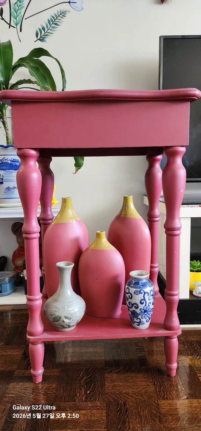 Pink accent table with decorative vases
