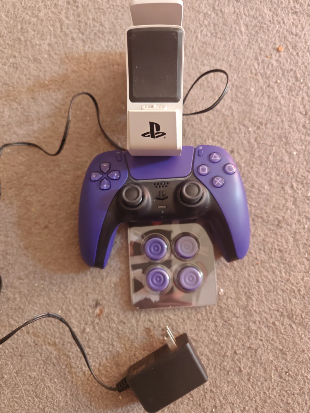 Purple PS5 controller with thumb caps and a charging stand