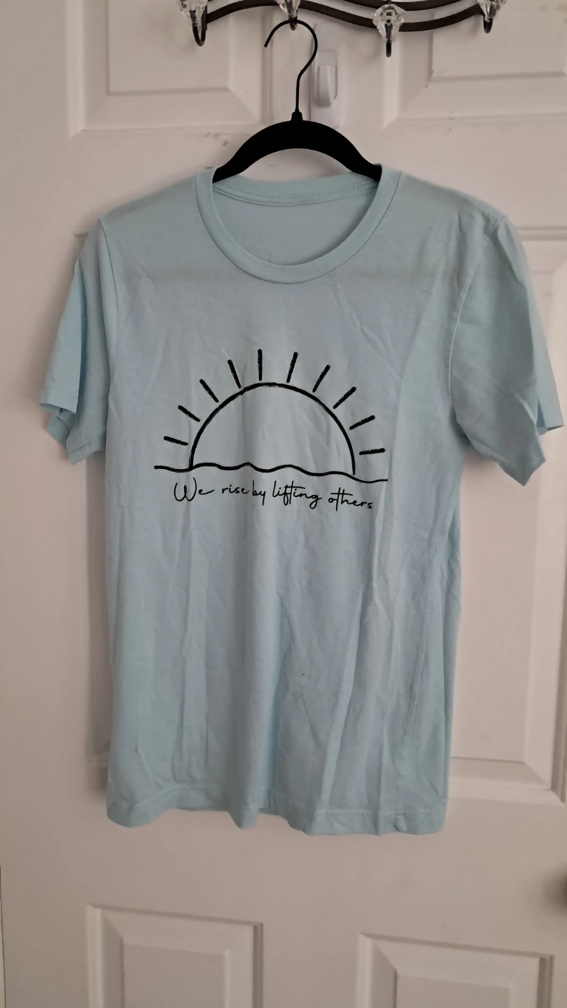 Light Blue T-Shirt with "We rise by lifting others" Graphic