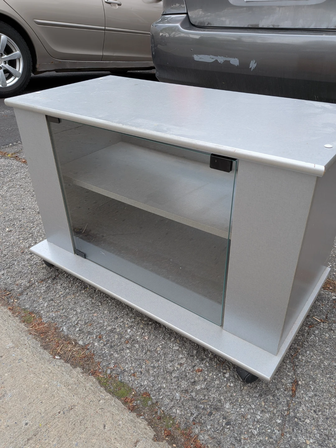 Meuble TV gris avec porte vitrée et roulettes