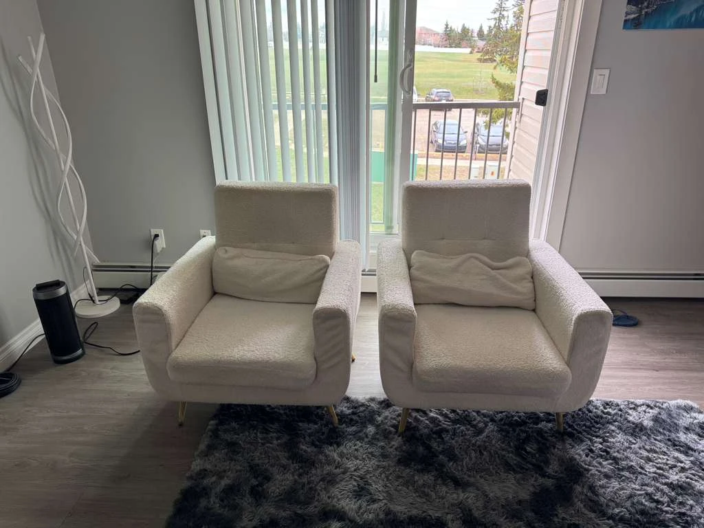 A pair of used tufted polyester armchairs