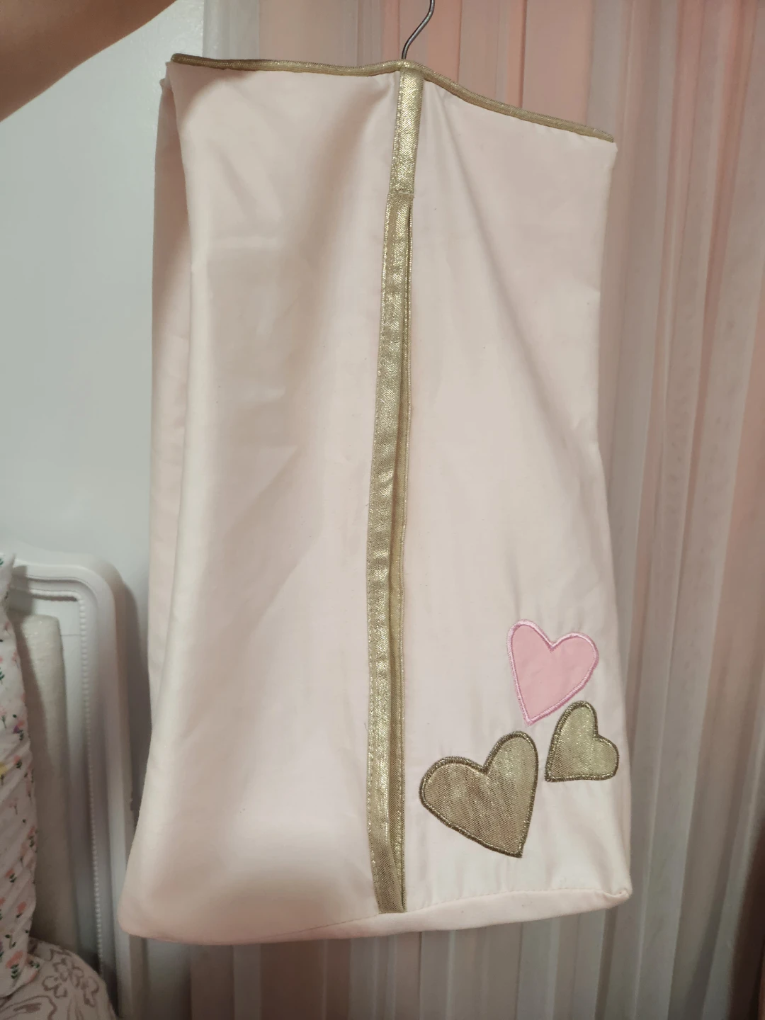 Pink garment bag with gold trim and heart appliques