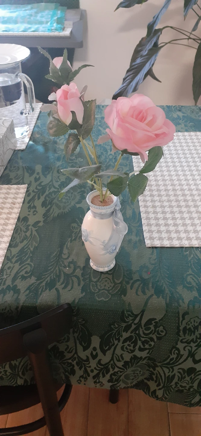 Pink artificial rose in small decorative vase