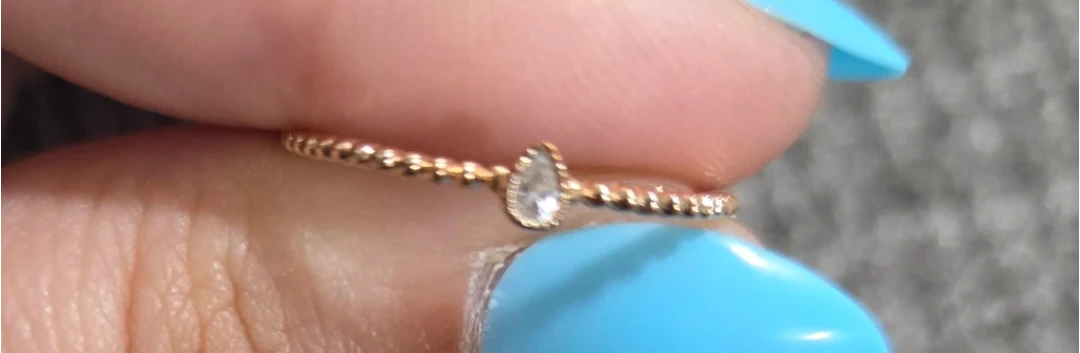 Gold beaded ring with a pear-shaped diamond accent