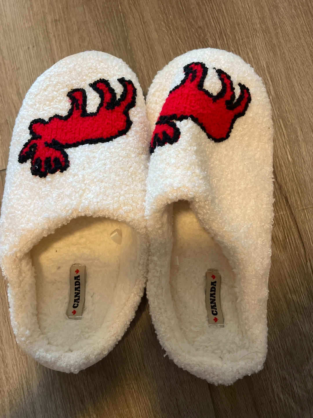 White fuzzy slippers with red Canadian beaver design
