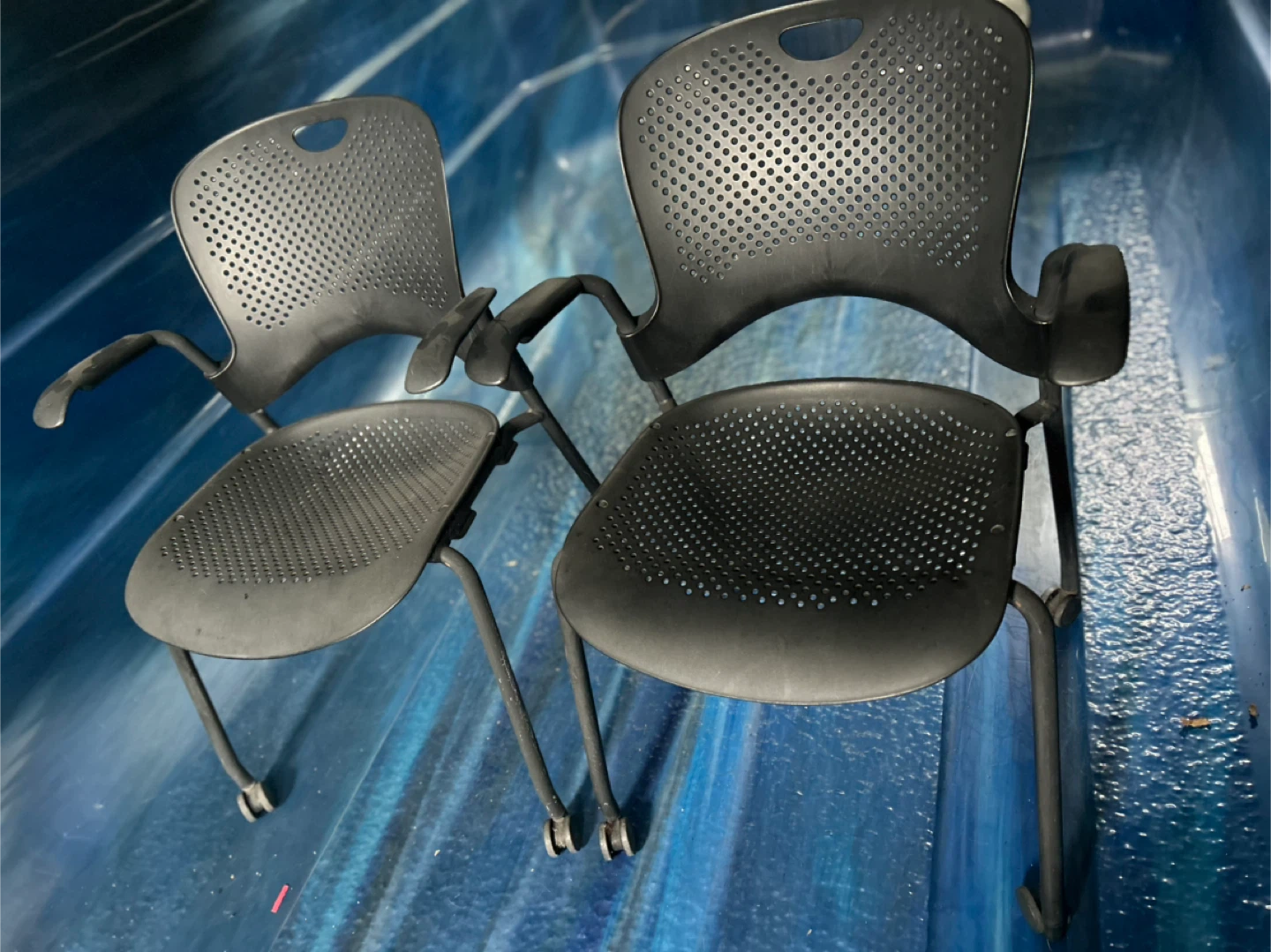 Two black plastic chairs with wheels